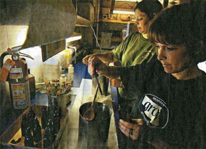 Kris Vrtiska (right), with Jennifer Uher working at her side, adds color to wax in a pour pot.